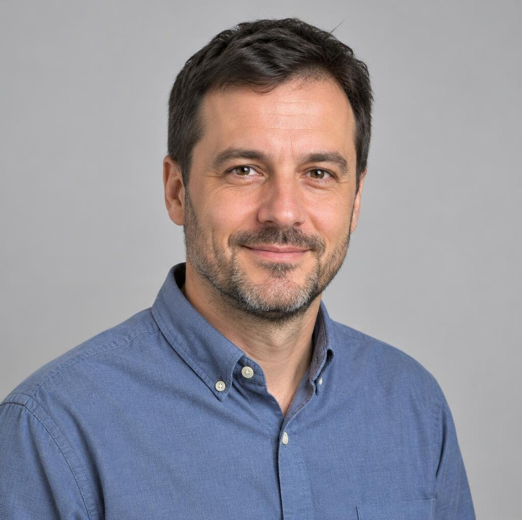 Portrait of a bearded man in a casual shirt smiling at the camera