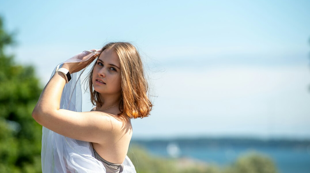 Portrait of a young woman with light brown hair smiling outdoors